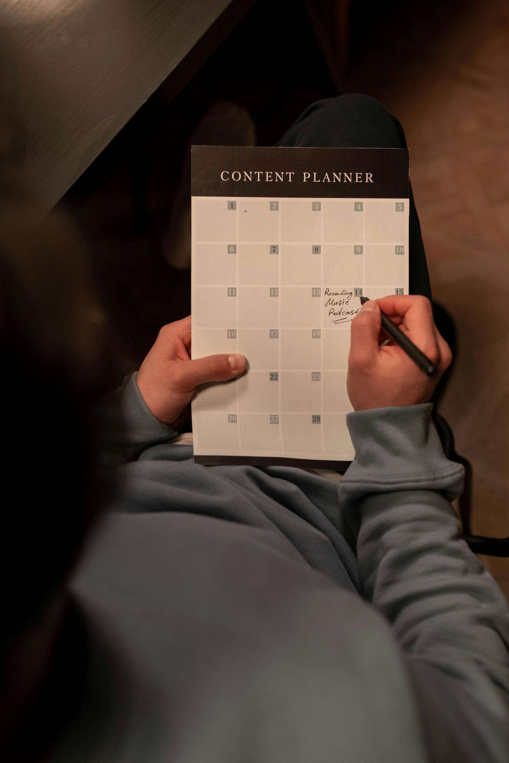 Person planning content on a calendar in a cozy indoor setting.